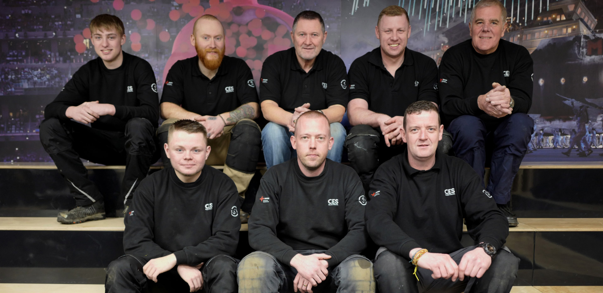 Eight men in CES shirts sat together